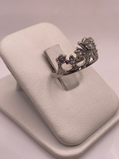Anillo de plata con piedra blanca engastada, vista lateral mostrando los detalles decorativos