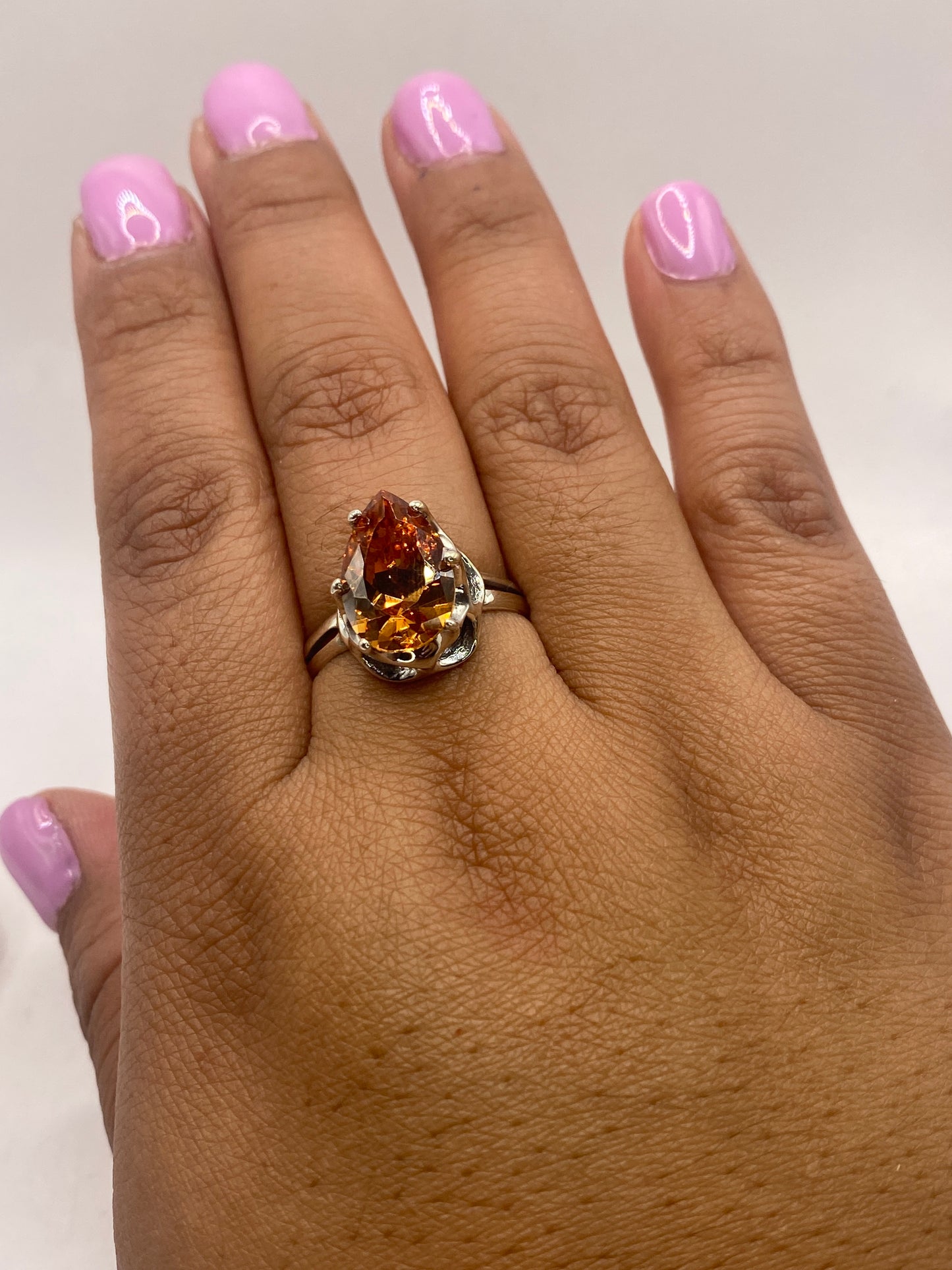 Anillo de plata en la mano de mujer con manicura, brillo del solitario café bajo luz natural