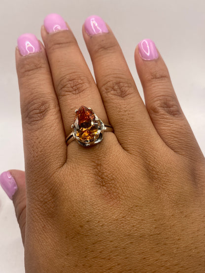 Anillo de plata en la mano de mujer con manicura, brillo del solitario café bajo luz natural