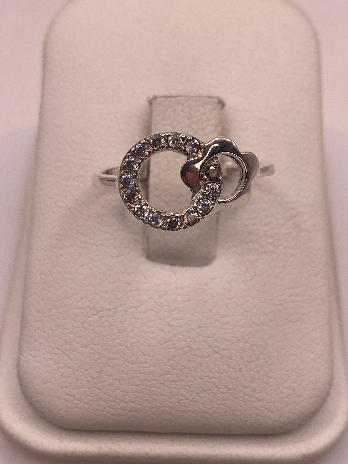 Anillo de plata solitario con circonia blanca brillante en mano de mujer con esmalte rosa