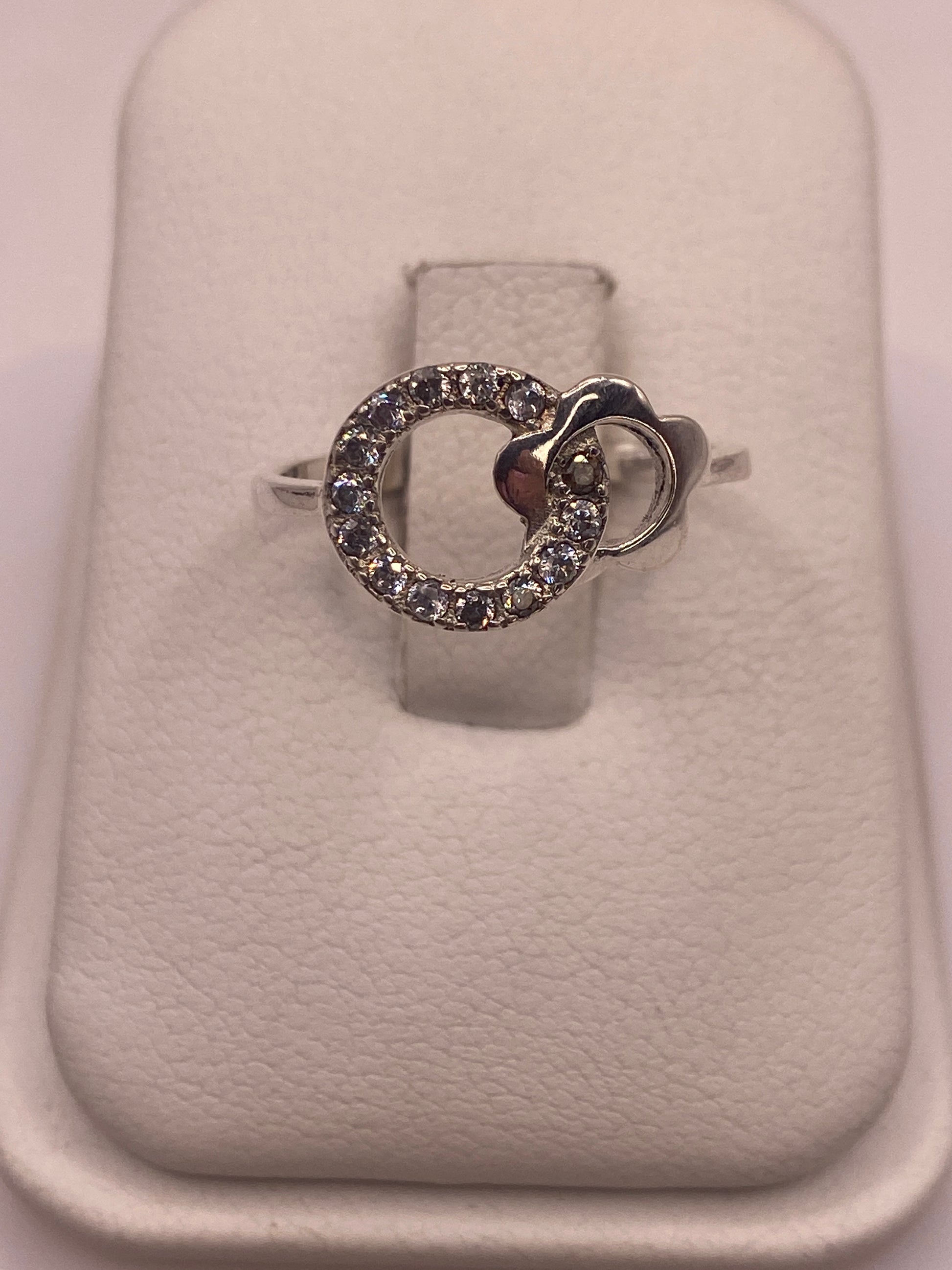 Anillo de plata solitario con circonia blanca brillante en mano de mujer con esmalte rosa