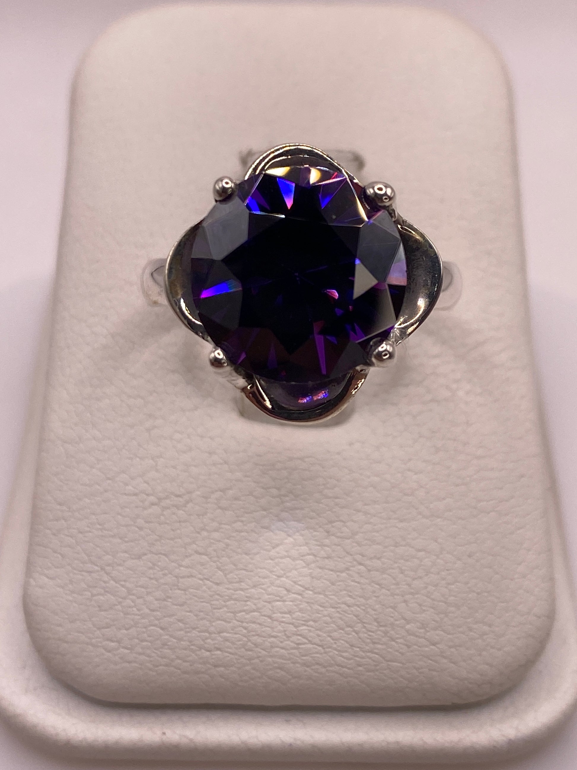 Anillo solitario de plata con circonia morada facetada sobre terciopelo blanco