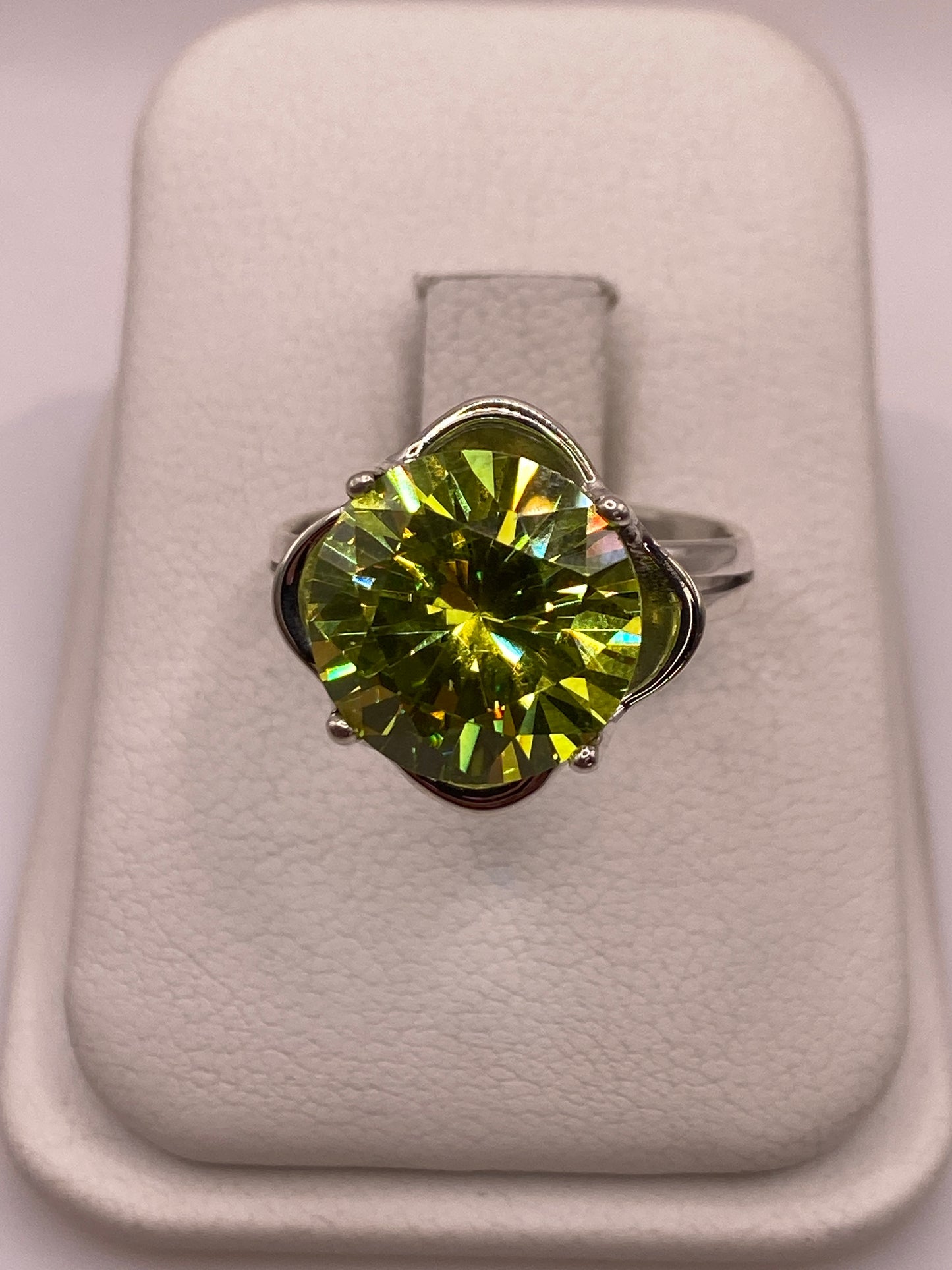 Anillo de plata solitario con circonia verde limón facetada, sobre almohada blanca