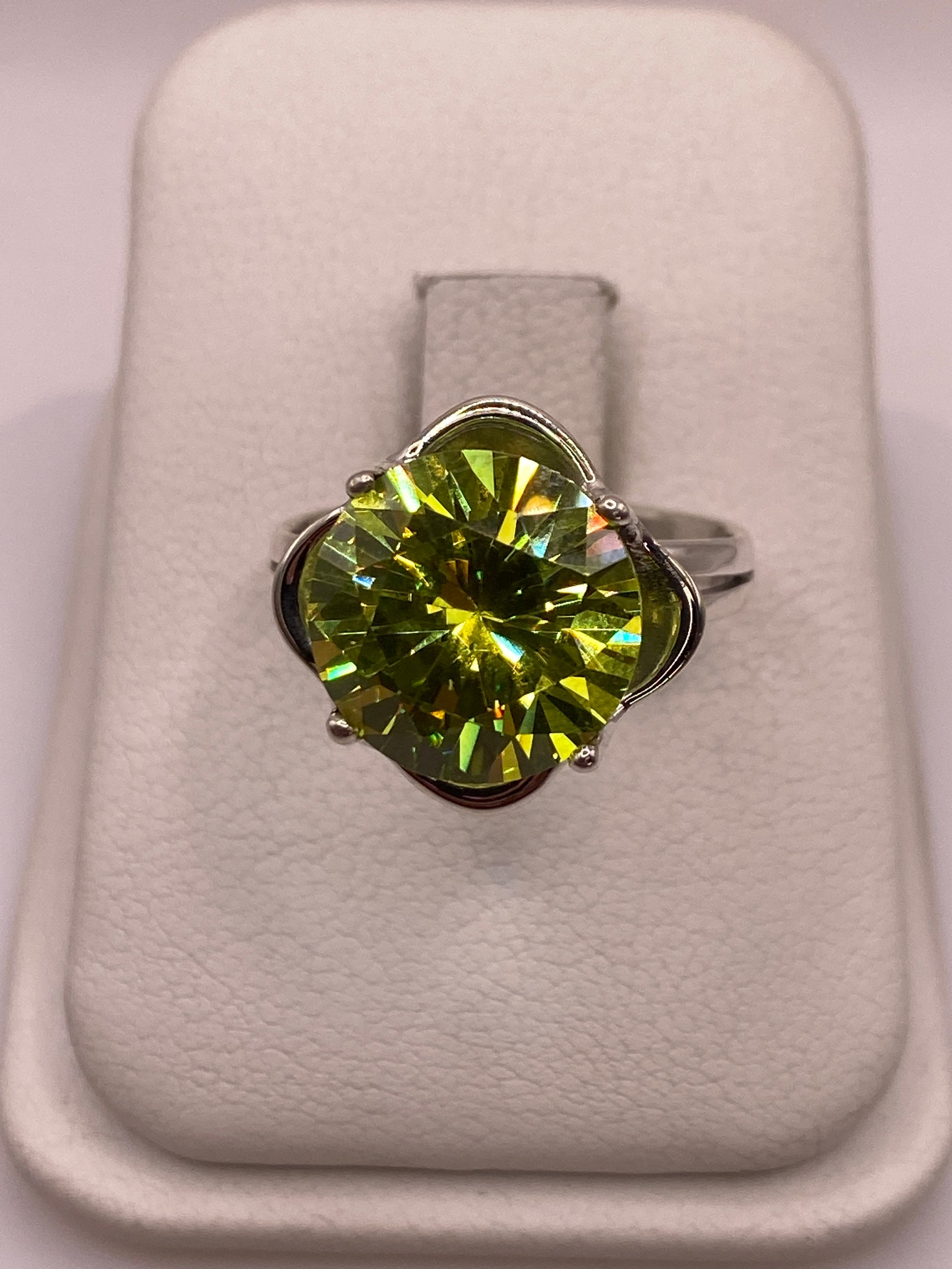 Anillo de plata solitario con circonia verde limón facetada, sobre almohada blanca