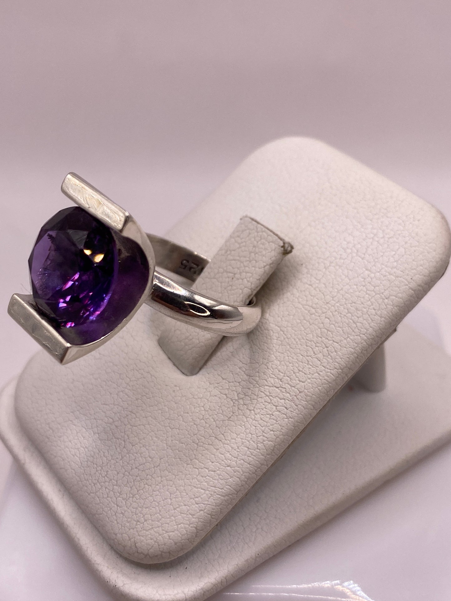 Vista lateral del anillo de coctel morado mostrando el engaste rectangular y la banda pulida