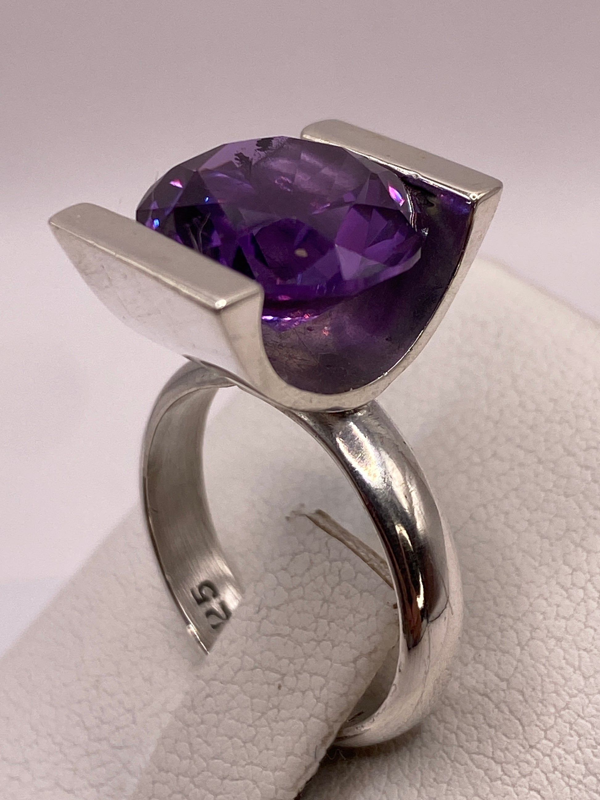Circonia morada brillante en primer plano, anillo en mano femenina con manicura morada
