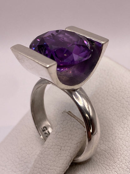Circonia morada brillante en primer plano, anillo en mano femenina con manicura morada