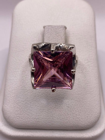 Anillo de plata solitario con circonia rosa facetada, vista frontal sobre cojín blanco