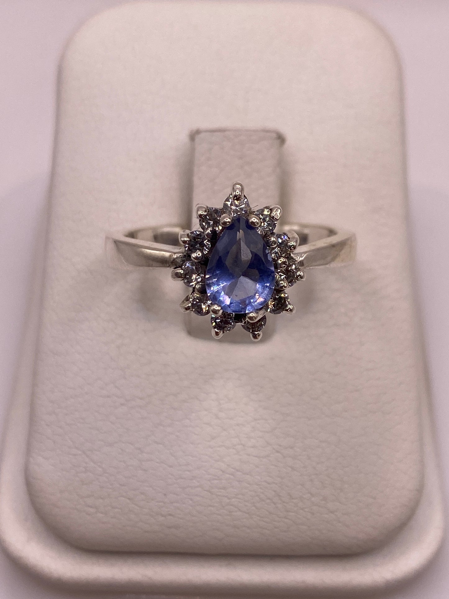 Anillo solitario de plata con circonia azul en soporte blanco, vista frontal