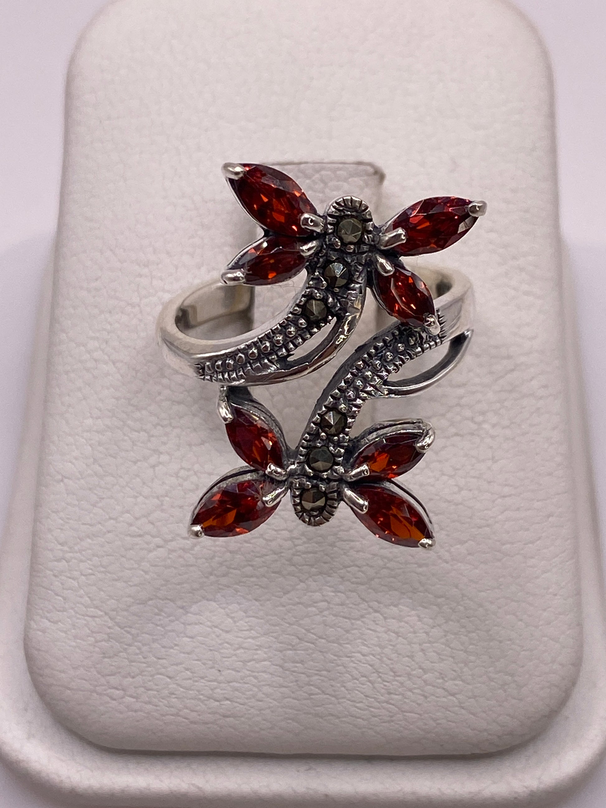 Anillo de plata mariposa con circonias ámbar y blancas en la mano de una mujer con uñas moradas