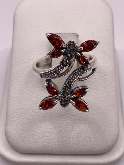 Anillo de plata mariposa con circonias ámbar y blancas en la mano de una mujer con uñas moradas