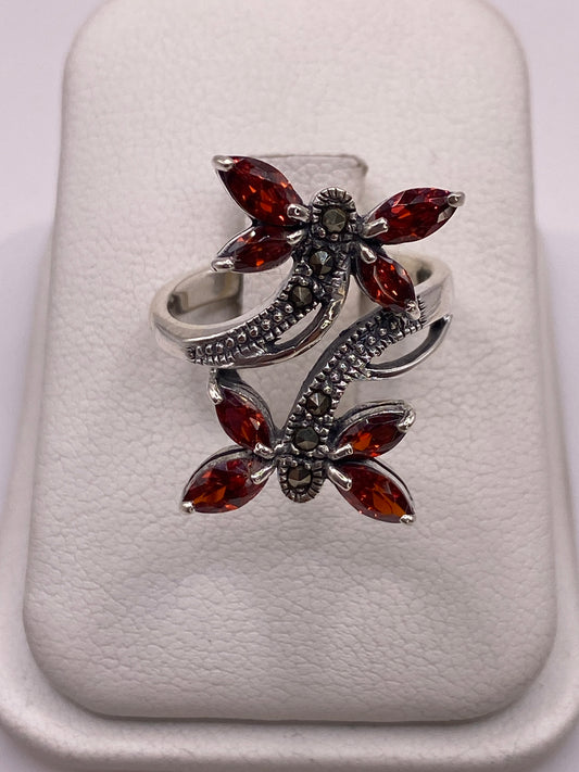 Anillo de plata mariposa con circonias ámbar y blancas en la mano de una mujer con uñas moradas