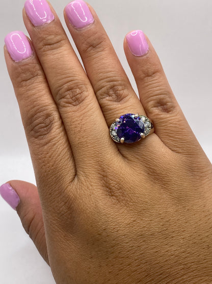 Anillo solitario de coctel morado en mano con uñas mauve, luz natural