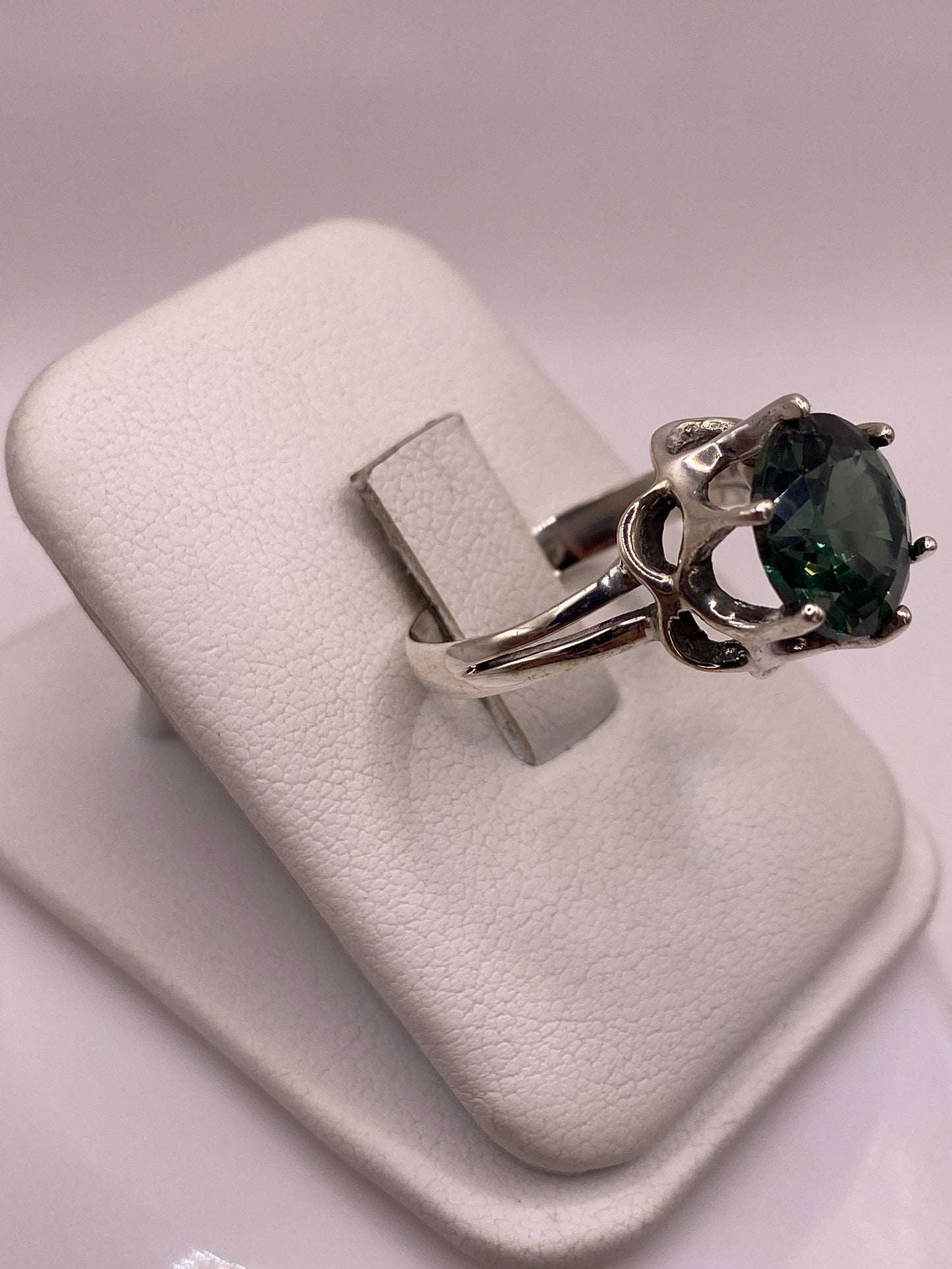 Detalle lateral del anillo mostrando la corona tallada en plata y la talla facetada de la circonia
