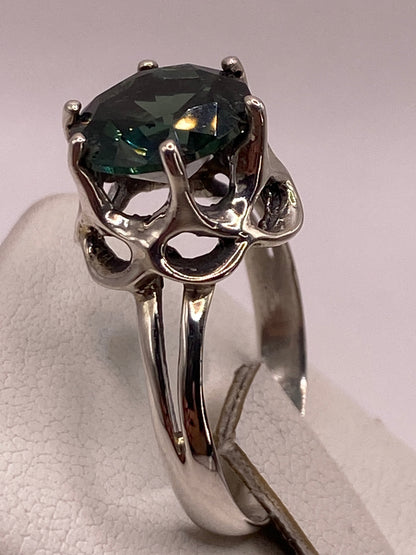 Anillo solitario verde en la mano luciendo el brillo diamantino de la piedra
