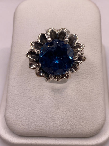 Anillo solitario de plata con circonia azul facetada sobre fondo blanco