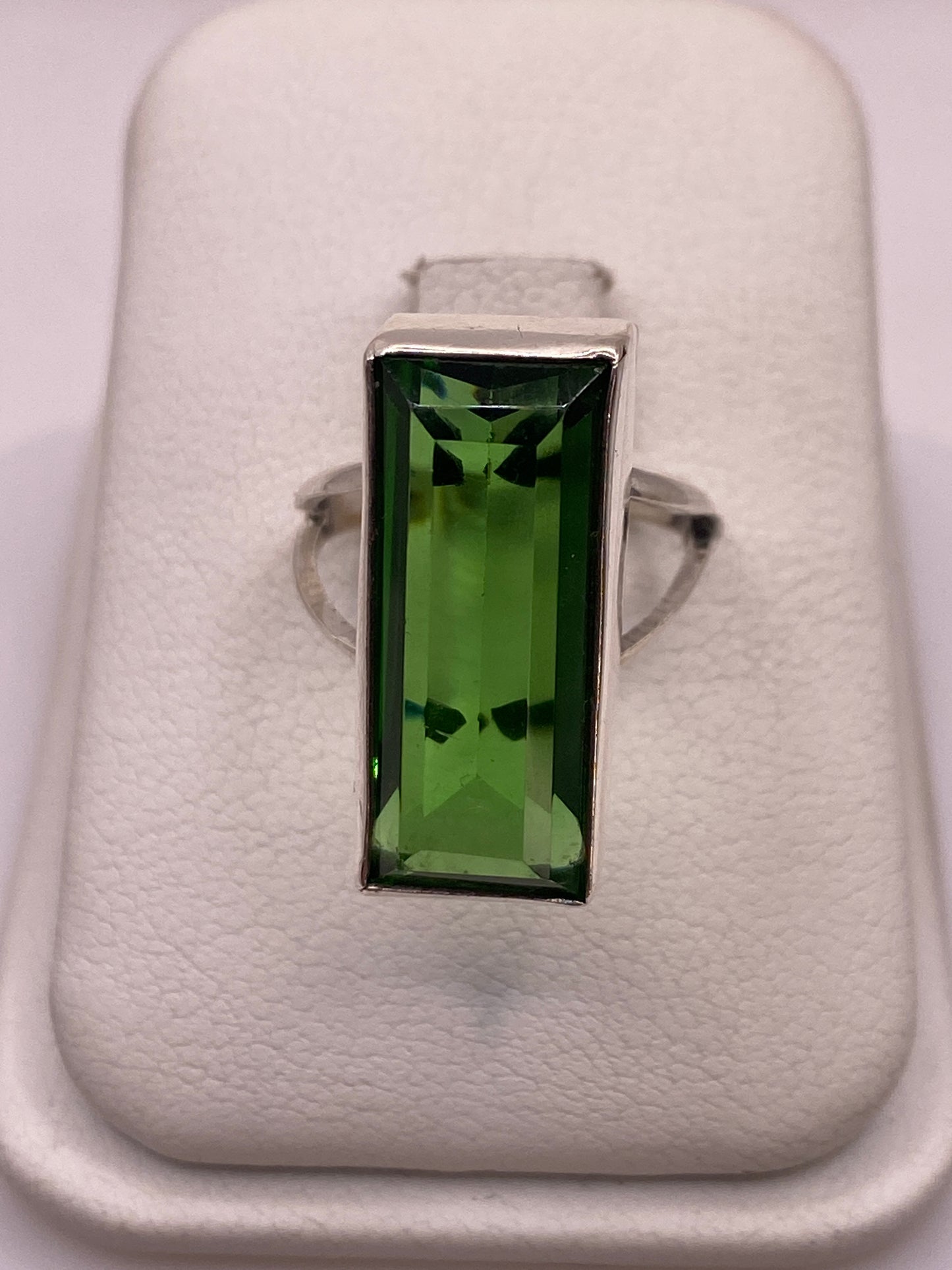 Anillo solitario de plata con circonia verde rectangular, vista frontal en estuche blanco