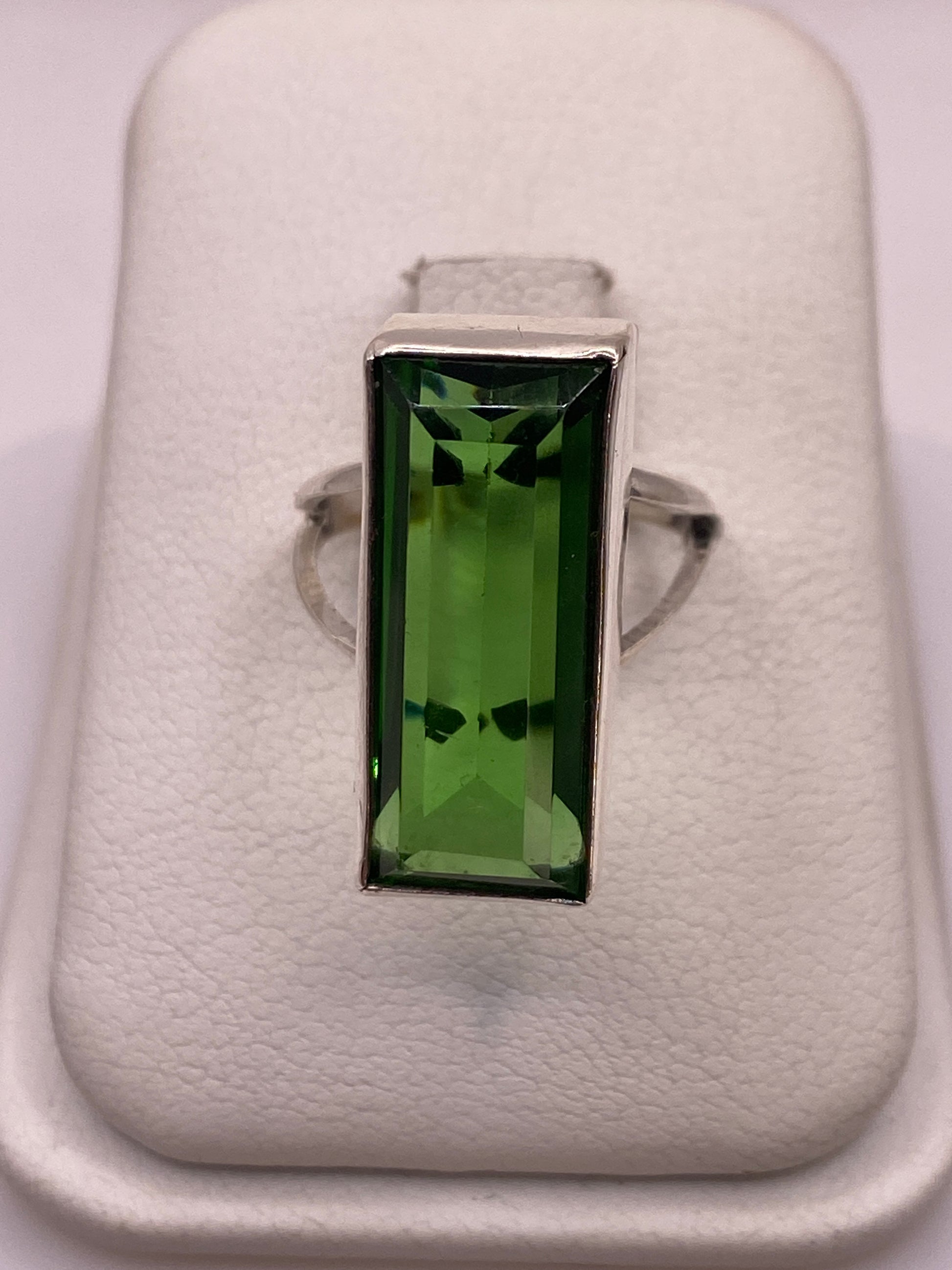 Anillo solitario de plata con circonia verde rectangular, vista frontal en estuche blanco