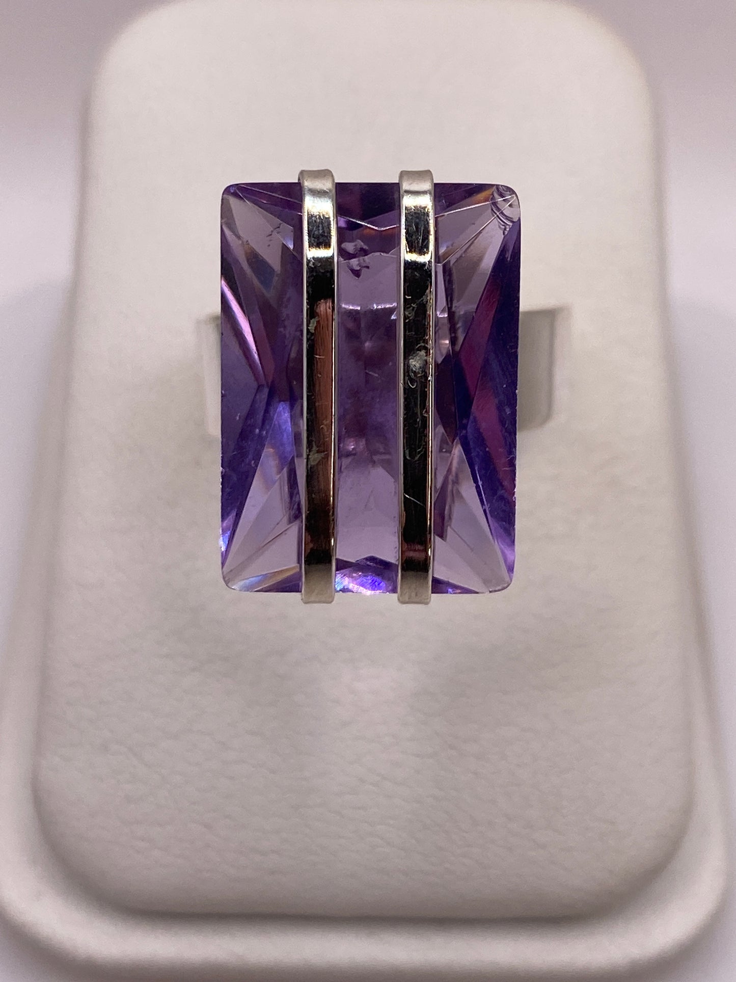 Anillo de plata .925 con circonia morada facetada sobre dedo, mostrando el brillo de la piedra