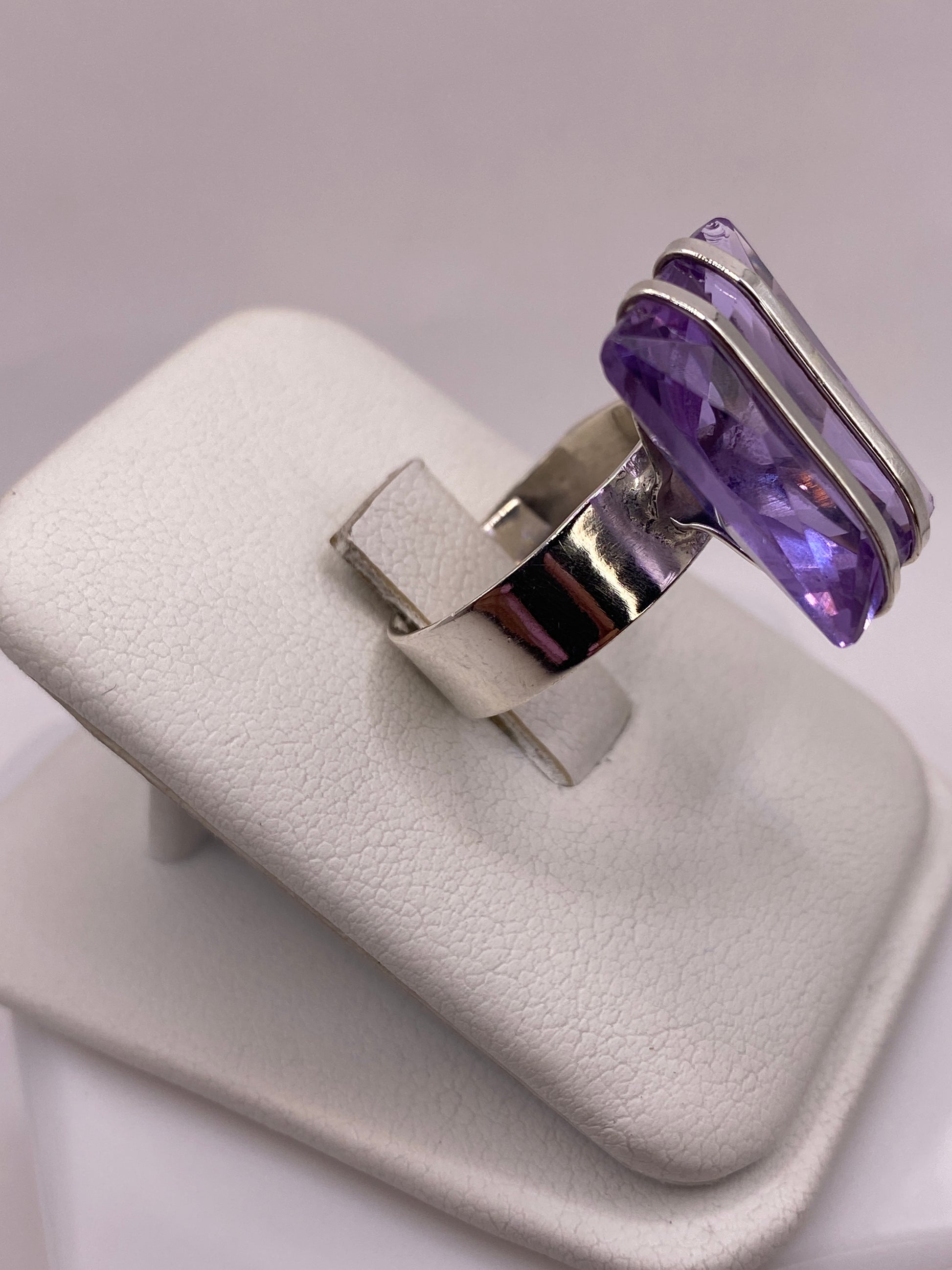 Vista frontal del anillo solitario con circonia morada en caja de presentación blanca