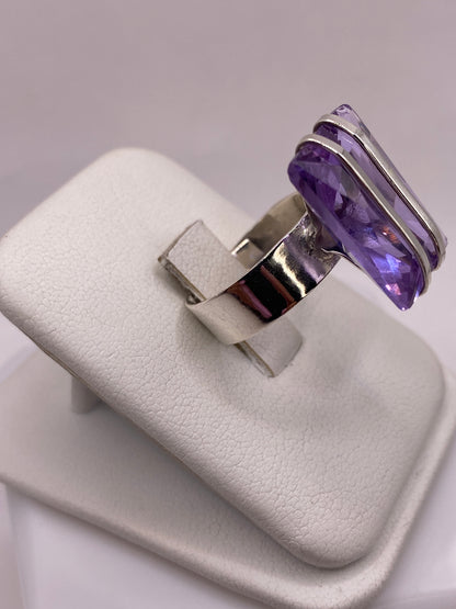 Vista frontal del anillo solitario con circonia morada en caja de presentación blanca