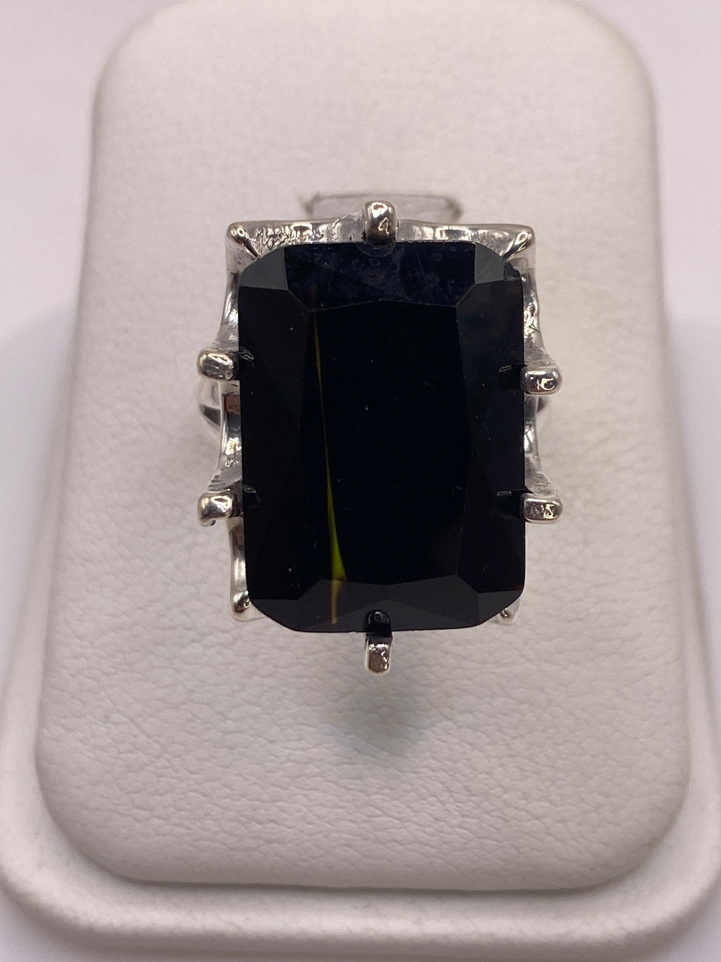 Anillo de plata .925 con circonia negra facetada grande en la mano de una mujer con esmalte rosa