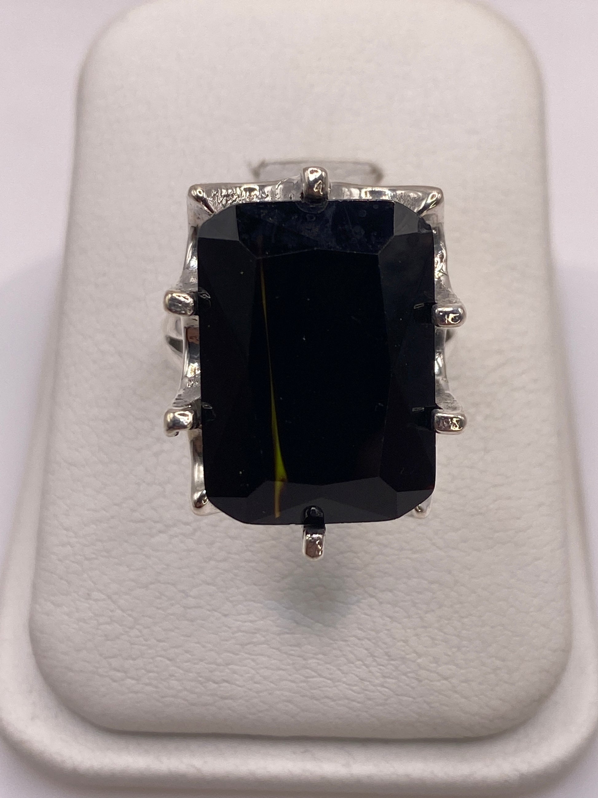 Anillo de plata .925 con circonia negra facetada grande en la mano de una mujer con esmalte rosa