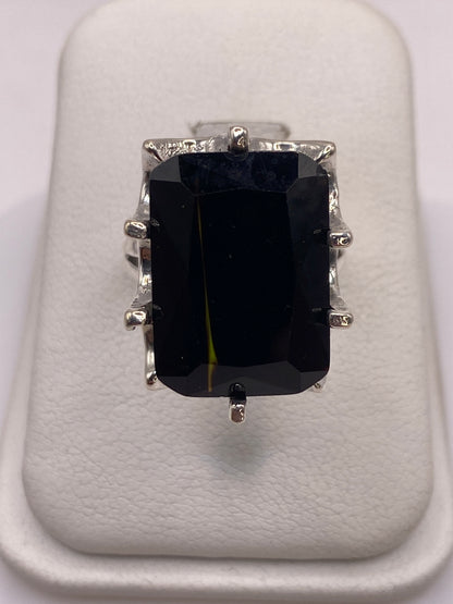 Anillo de plata .925 con circonia negra facetada grande en la mano de una mujer con esmalte rosa
