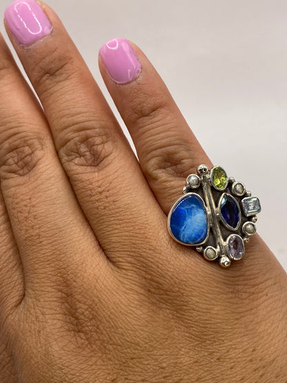 Anillo geométrico multicolor en dedo con brillo y fuego de las gemas bajo luz natural