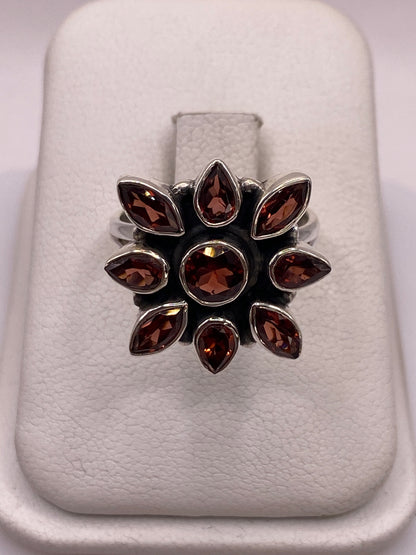 Anillo de plata floral con nueve circonias brillantes en la mano de una mujer