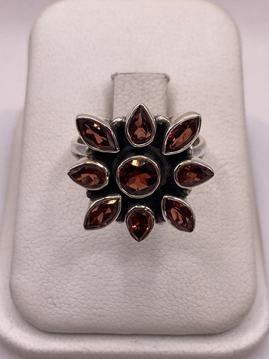 Anillo de plata floral con nueve circonias brillantes en la mano de una mujer