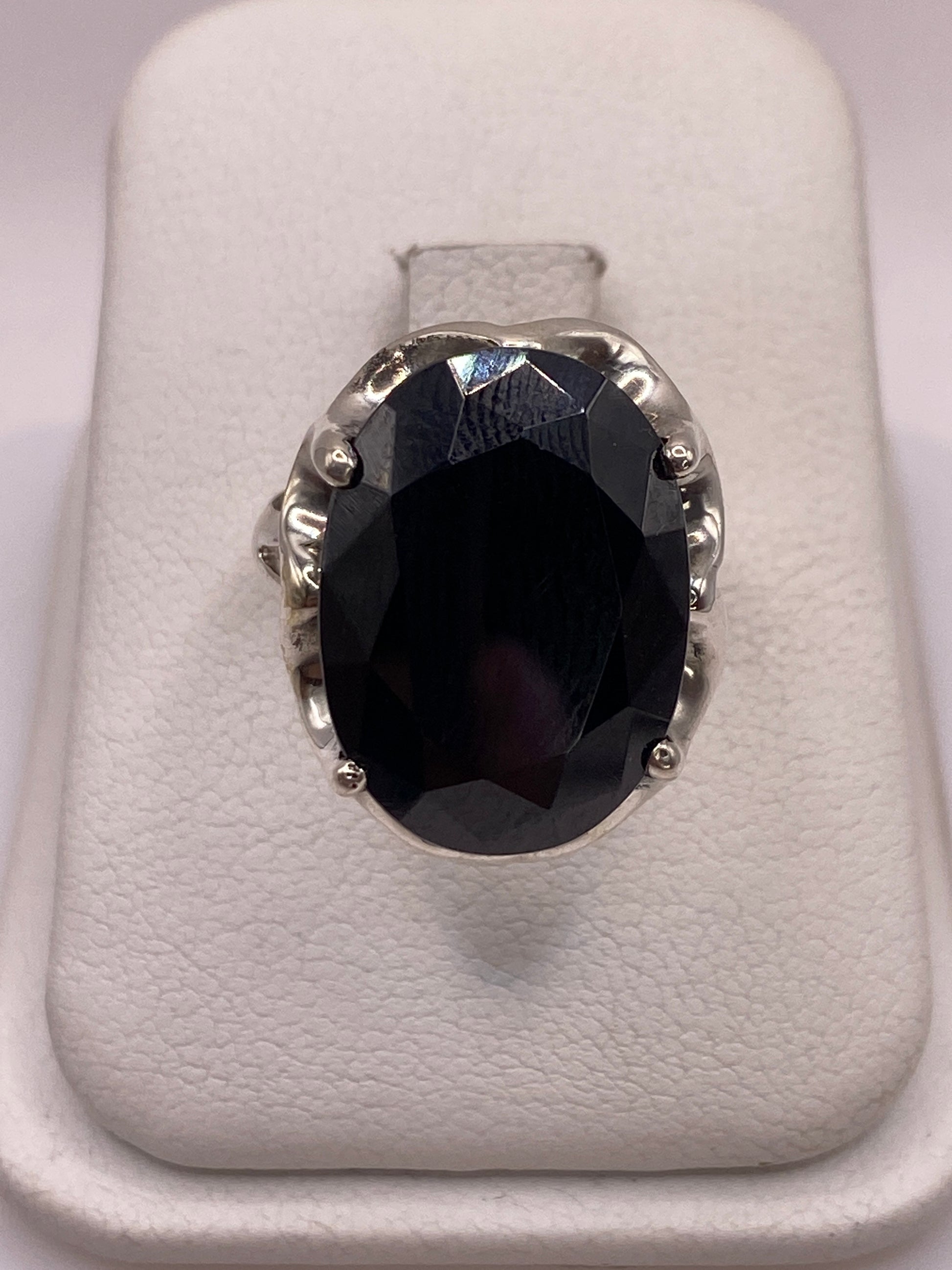 Anillo de plata solitario con circonia negra facetada sobre soporte blanco, vista frontal