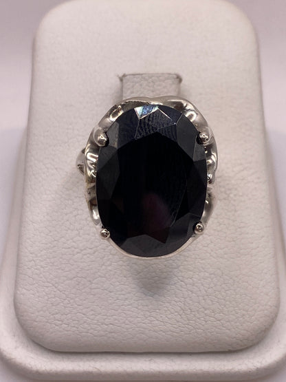 Anillo de plata solitario con circonia negra facetada sobre soporte blanco, vista frontal