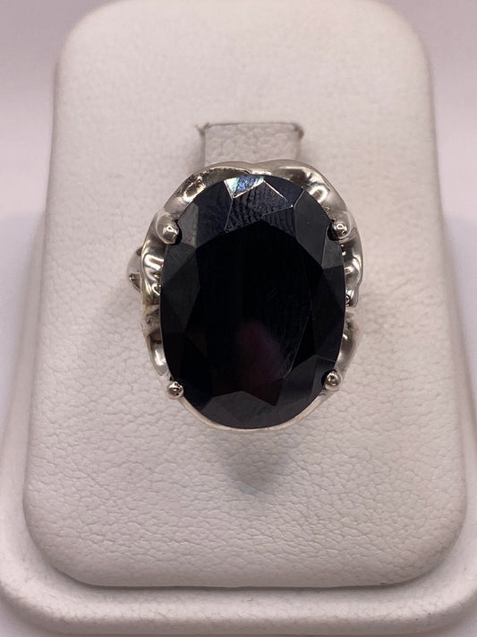 Anillo de plata solitario con circonia negra facetada sobre soporte blanco, vista frontal