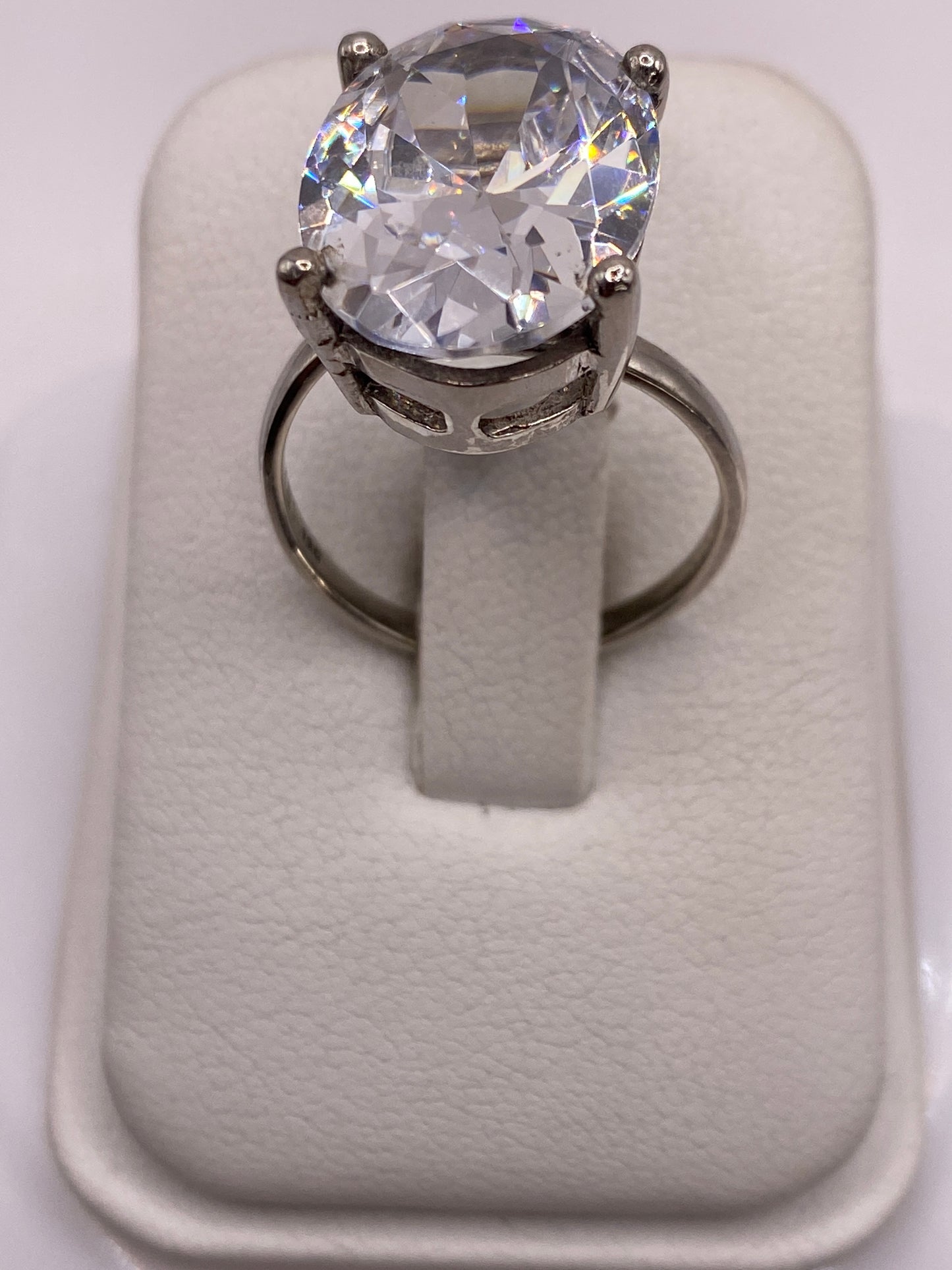Anillo solitario de plata con circonia blanca en la mano de una mujer con esmalte rosa