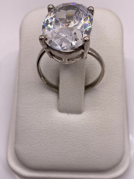 Anillo solitario de plata con circonia blanca en la mano de una mujer con esmalte rosa