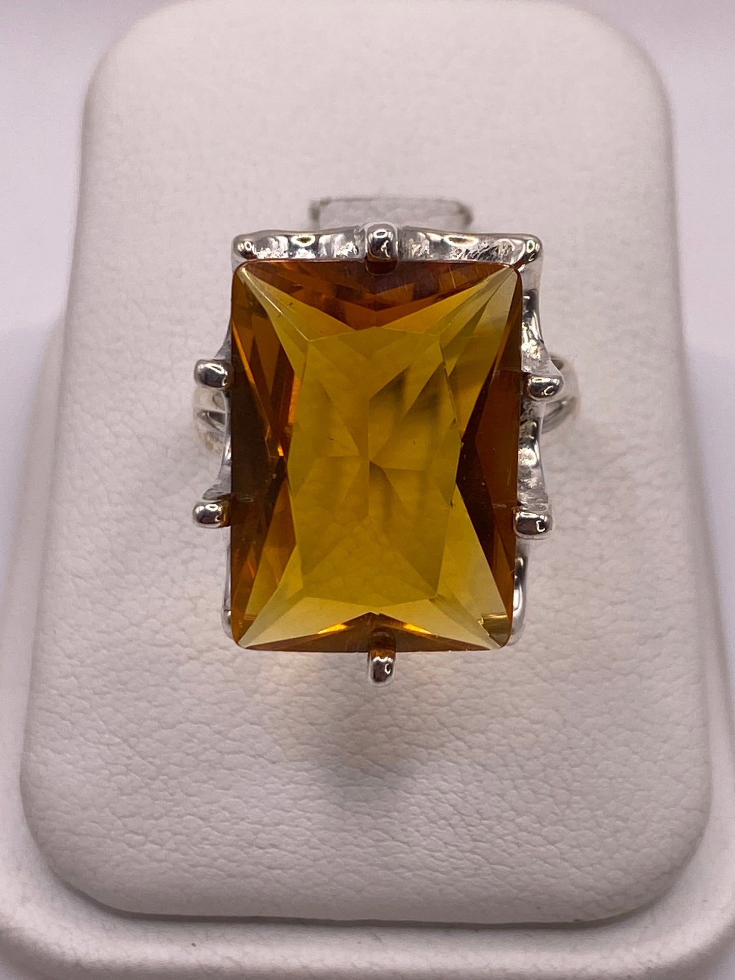 Anillo de plata solitario con circonia amarillo dorado facetada sobre fondo blanco