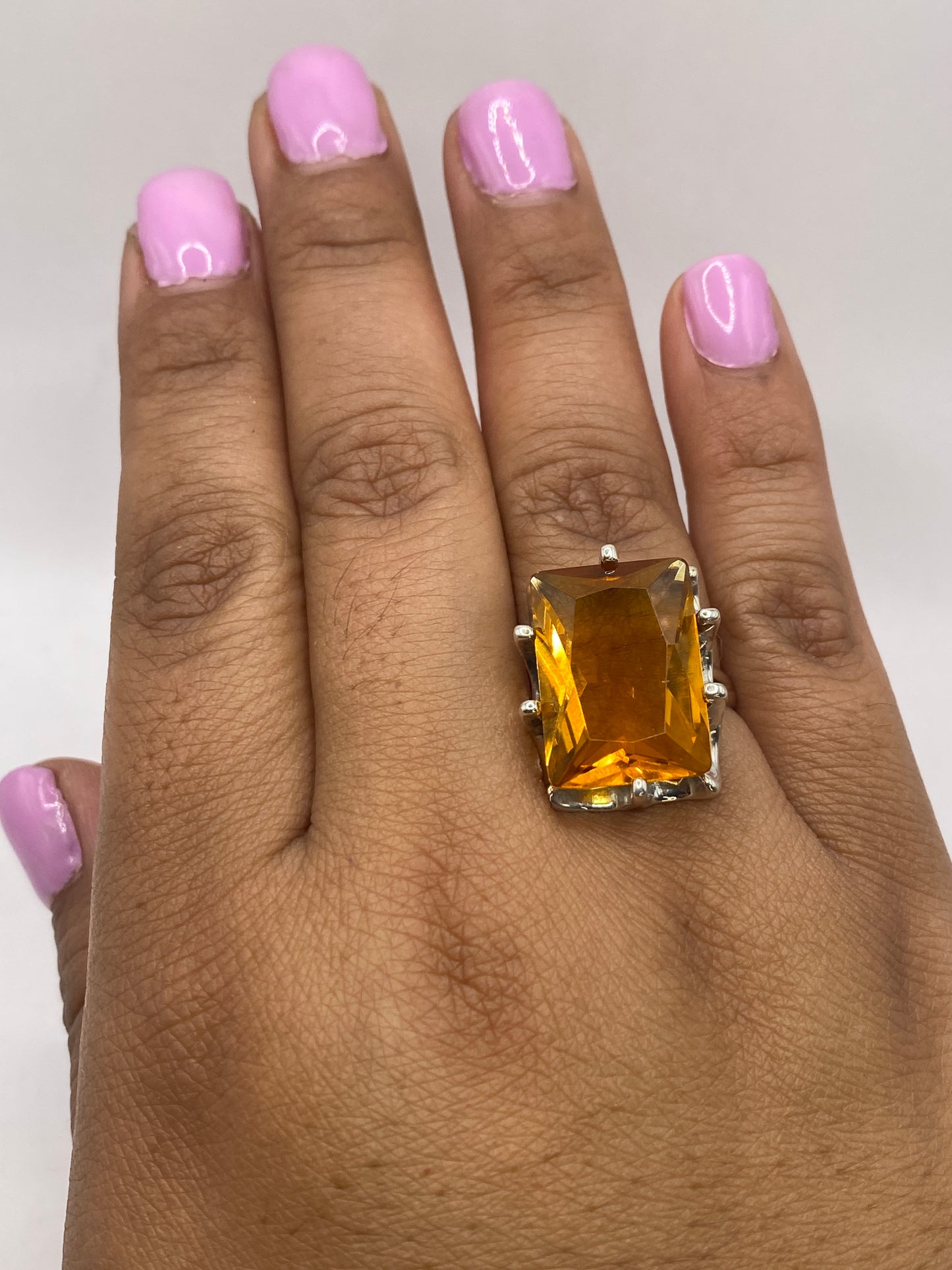 Anillo solitario en la mano de una mujer con manicura rosa brillante