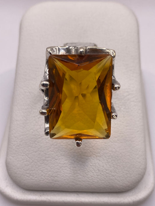 Anillo de plata solitario con circonia amarilla dorada sobre fondo blanco, vista frontal