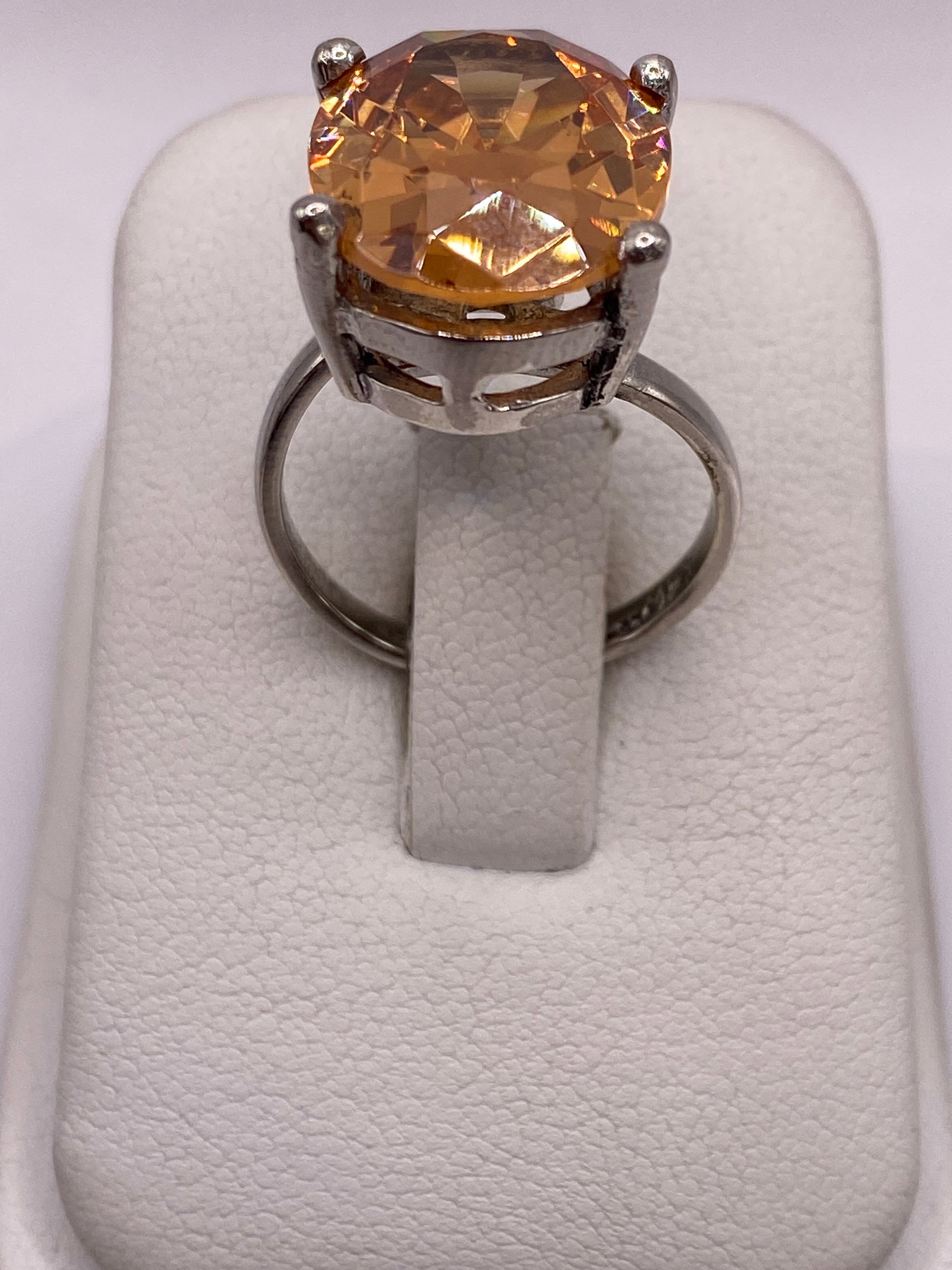 Anillo de plata .925 con circonia ámbar oval engastado a mano, visto de frente sobre dedo de mujer