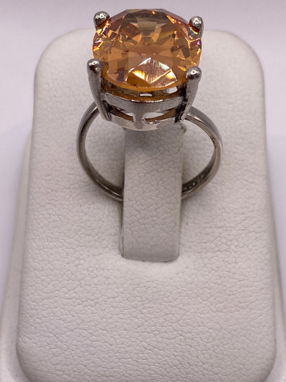 Anillo de plata .925 con circonia ámbar oval engastado a mano, visto de frente sobre dedo de mujer