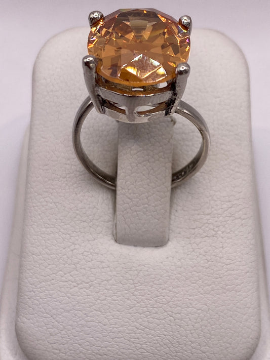 Anillo de plata .925 con circonia ámbar oval engastado a mano, visto de frente sobre dedo de mujer