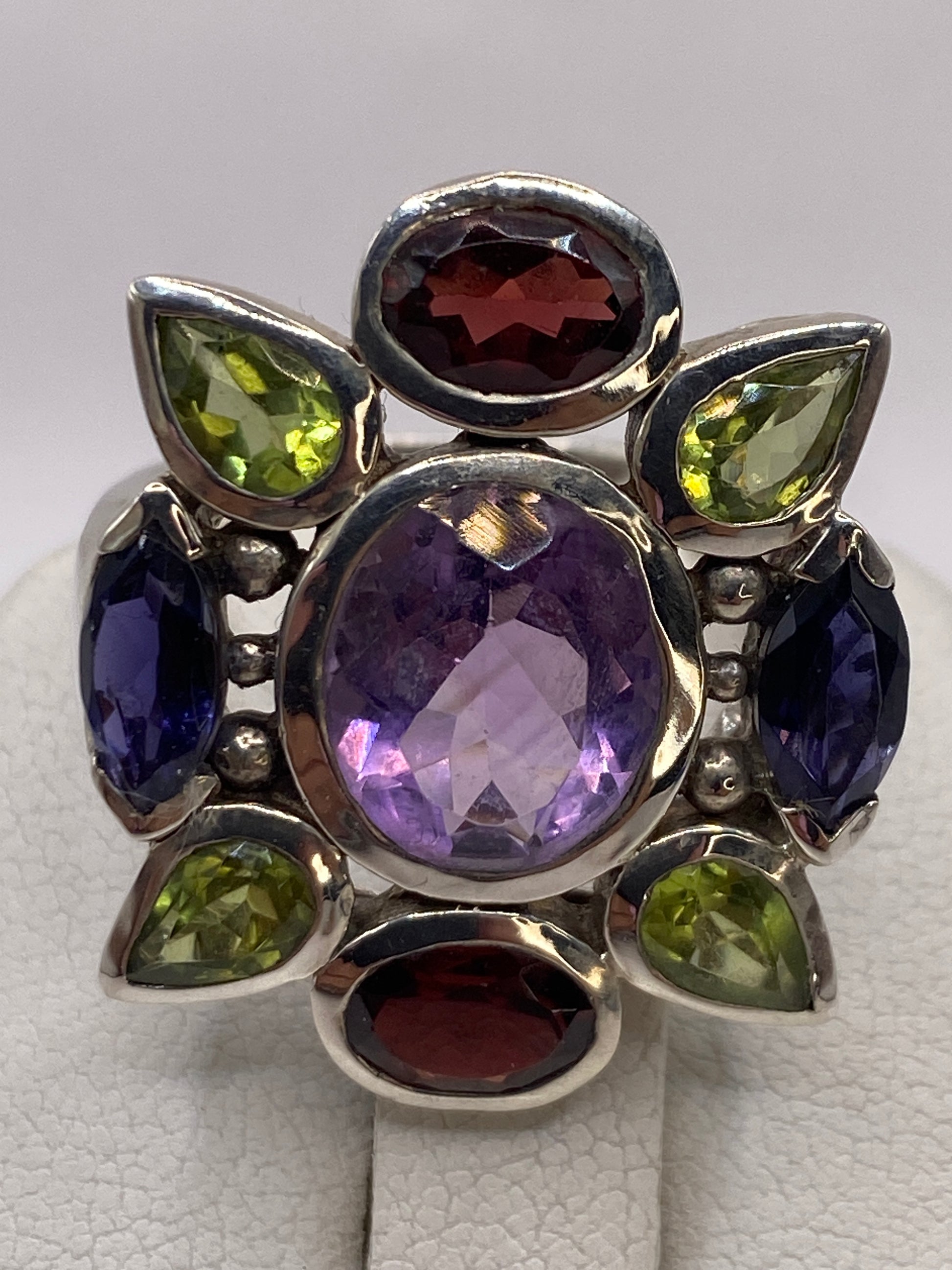 Anillo multicolor puesto en mano mostrando el brillo de las piedras y el pulido de la plata