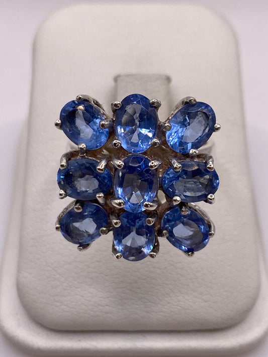Anillo de plata racimo con nueve circonias azules sobre dedo de mujer