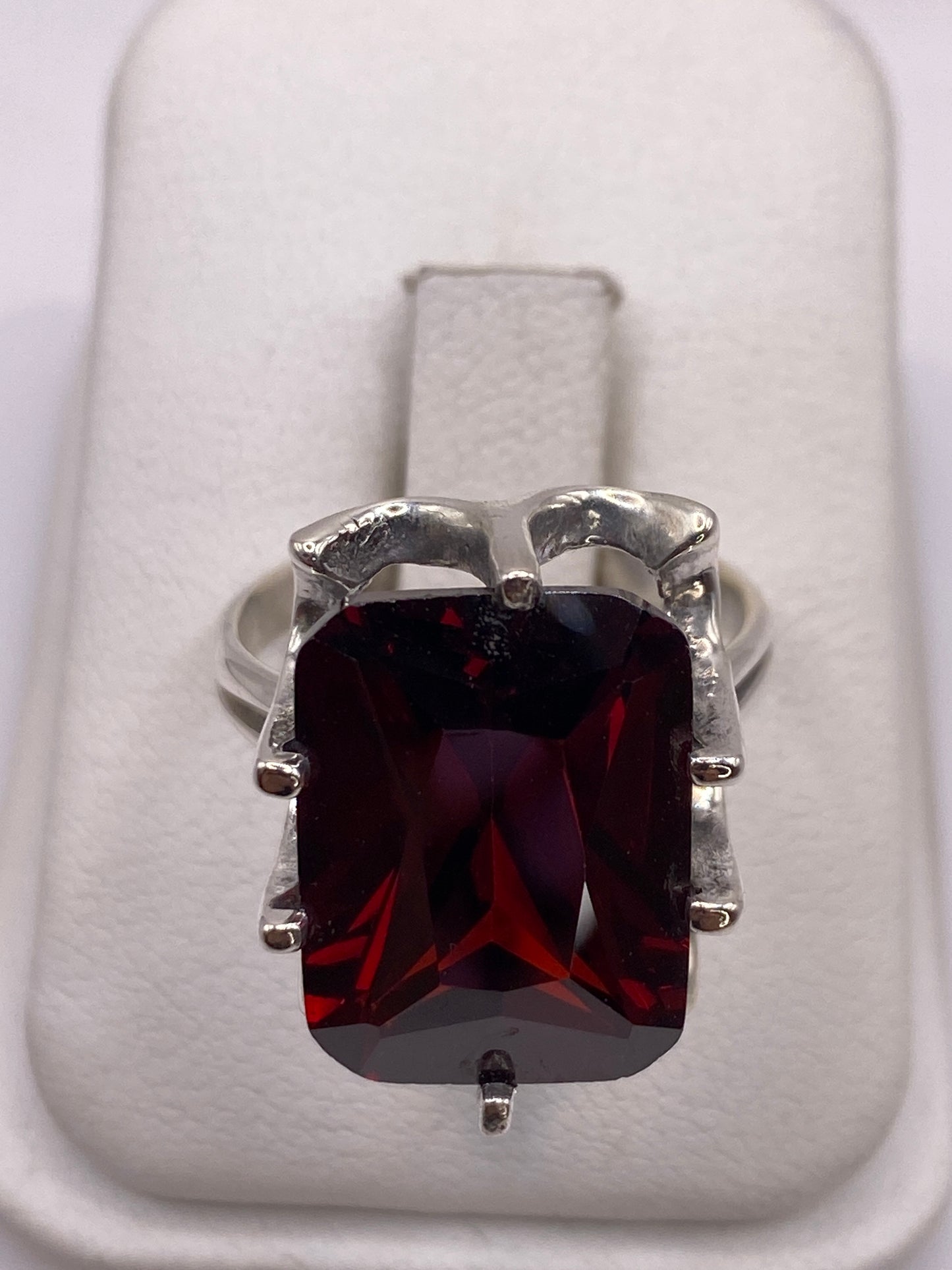 Anillo de plata con circonia roja rectangular engastada en mano de mujer adulta
