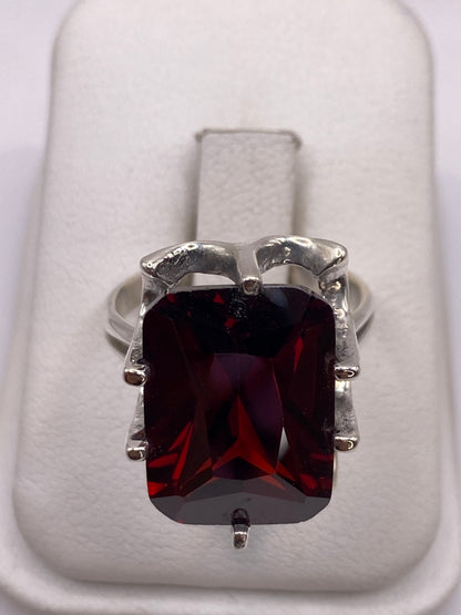 Anillo de plata con circonia roja rectangular engastada en mano de mujer adulta