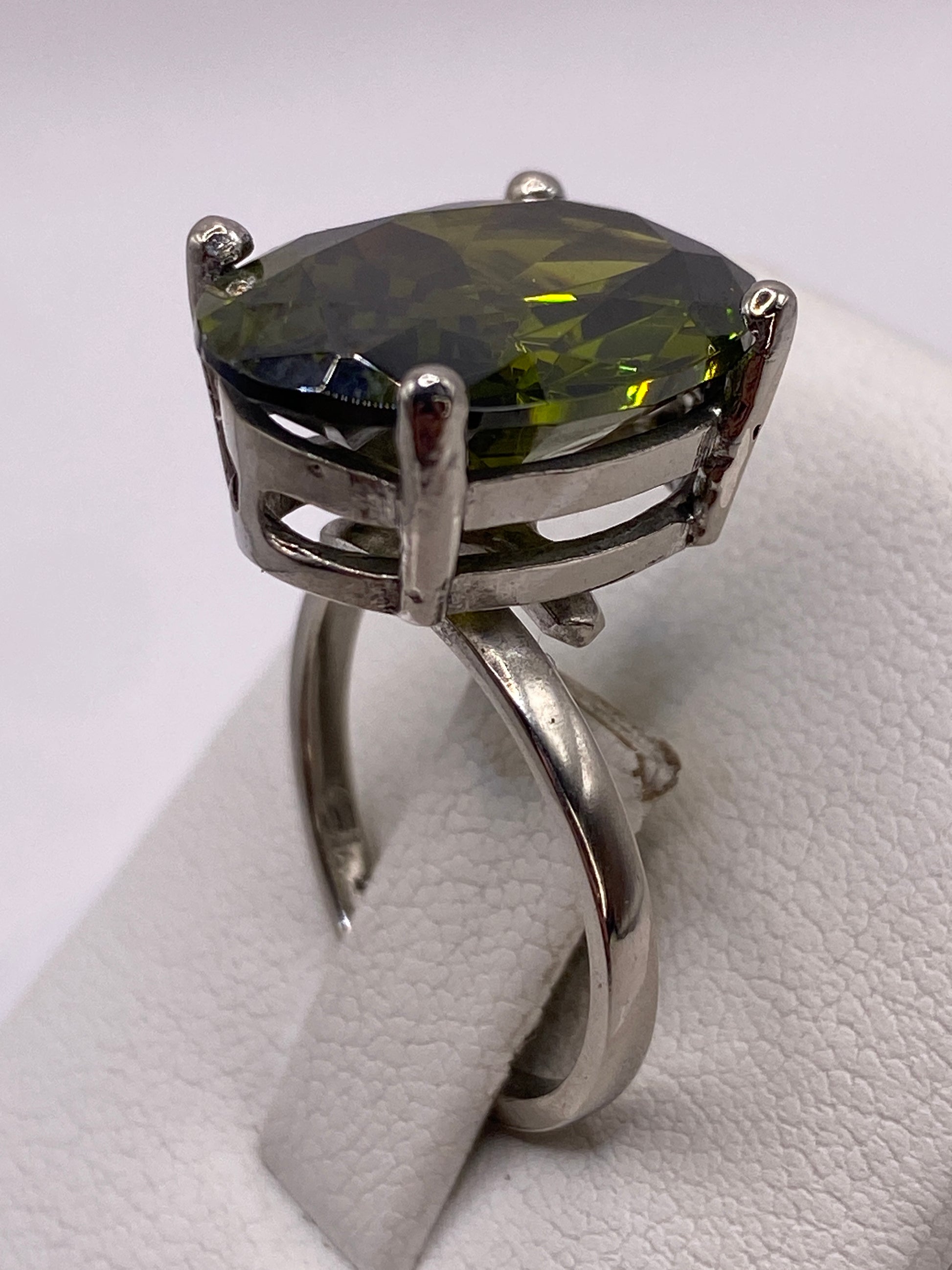 Anillo de plata con circonia verde olivo en dedo mostrando brillo intenso