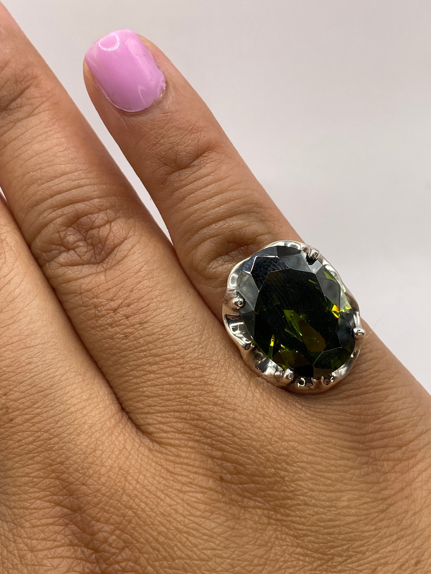 Anillo solitario en la mano mostrando el brillo verde olivo de la circonia