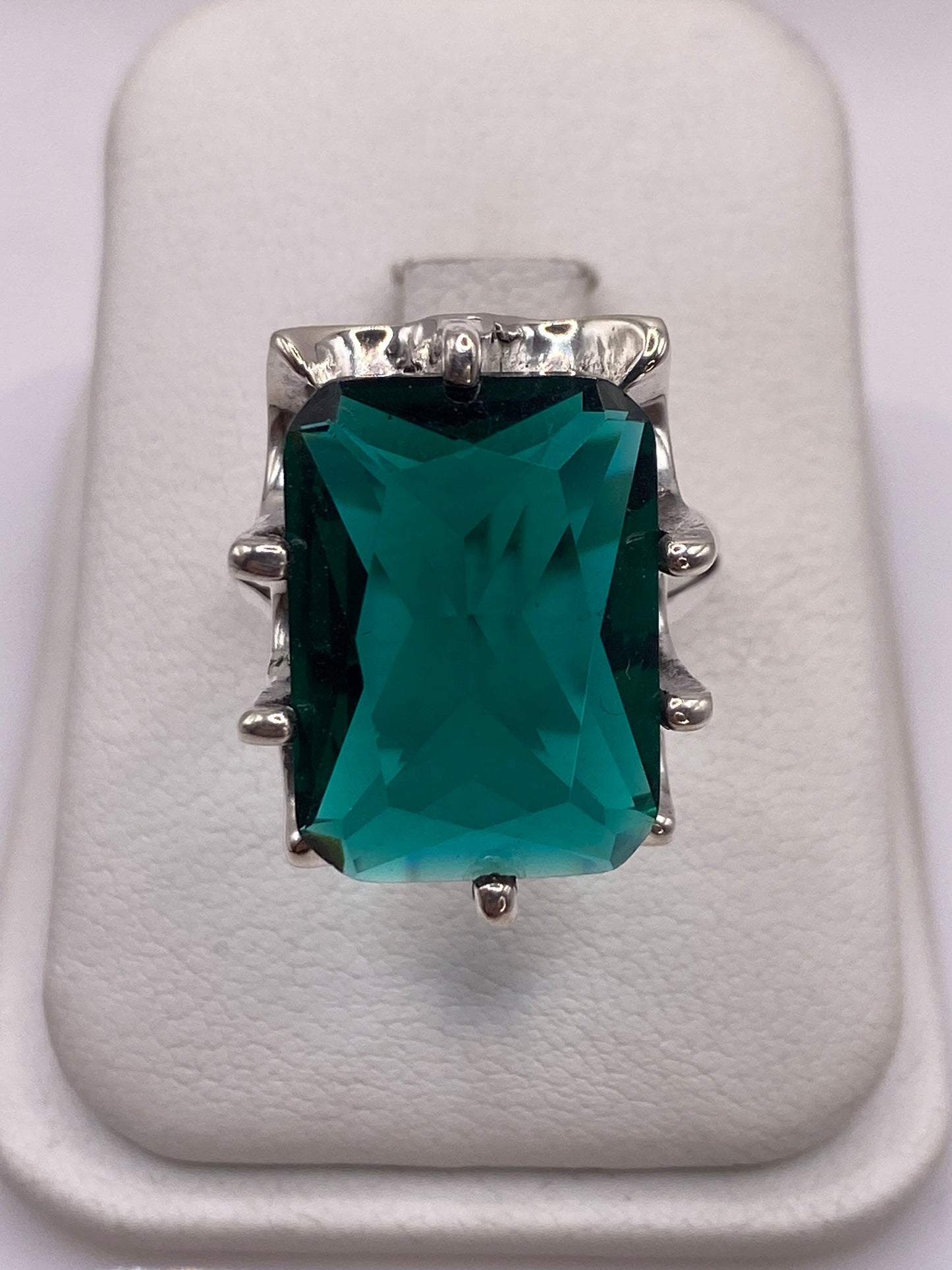 Anillo de plata solitario con circonia verde teal en la mano de una mujer