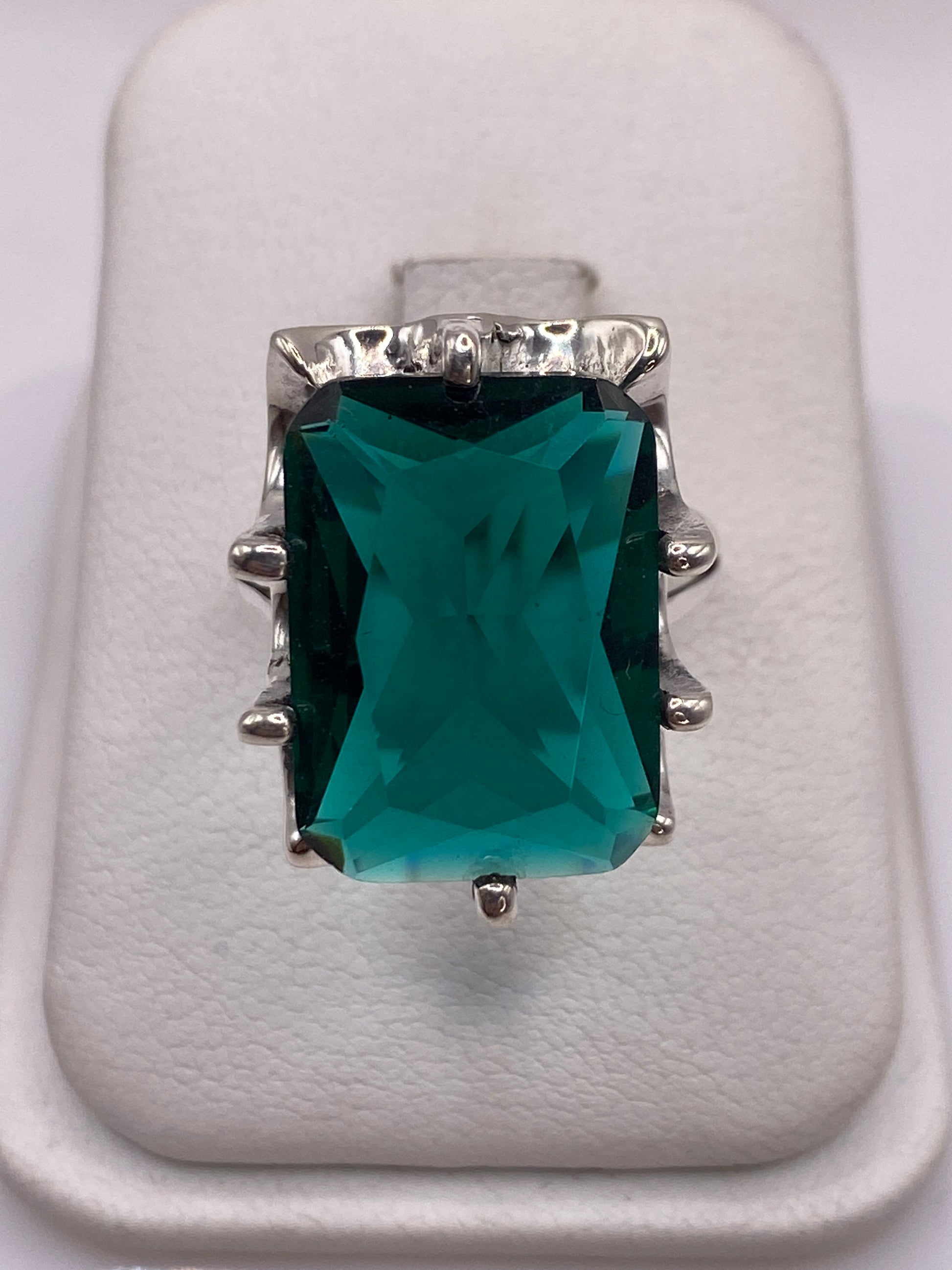 Anillo de plata solitario con circonia verde teal en la mano de una mujer